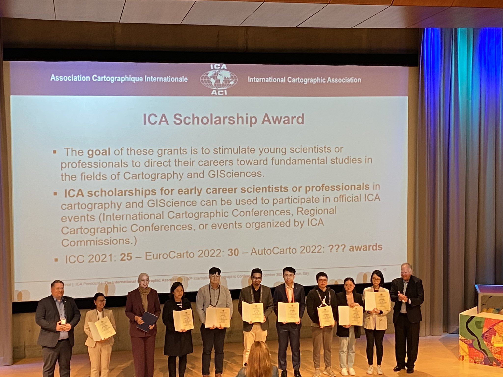 Winners of the ICA Scholarship Award stand in front of a stage to be honored for the achievement