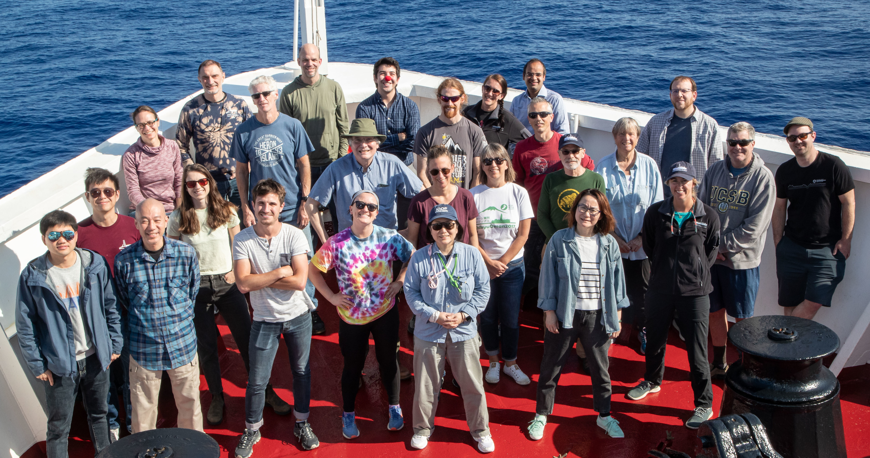 A group photo of researchers on the bow of a ship at sea.