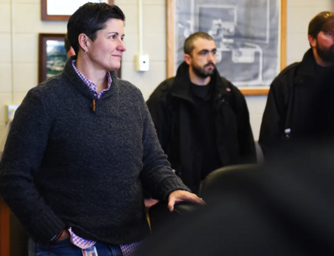 Beth Skinner standing in a conference room talking with coworkers