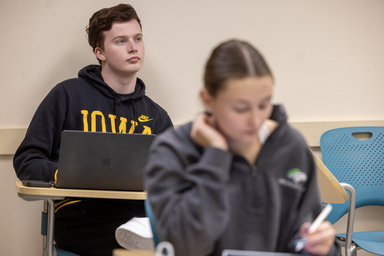 A student in the back of the classroom actively listening