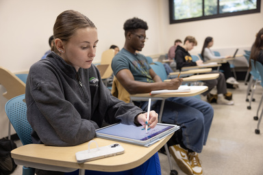 A student takes notes on an electronic tablet.