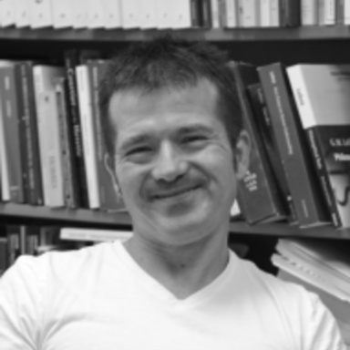 Black and white photo of David Cunning in front of a full bookshelf