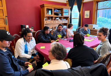 Image: students seated at a table in discussion