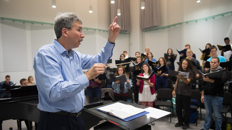 man conducting students in a choir room