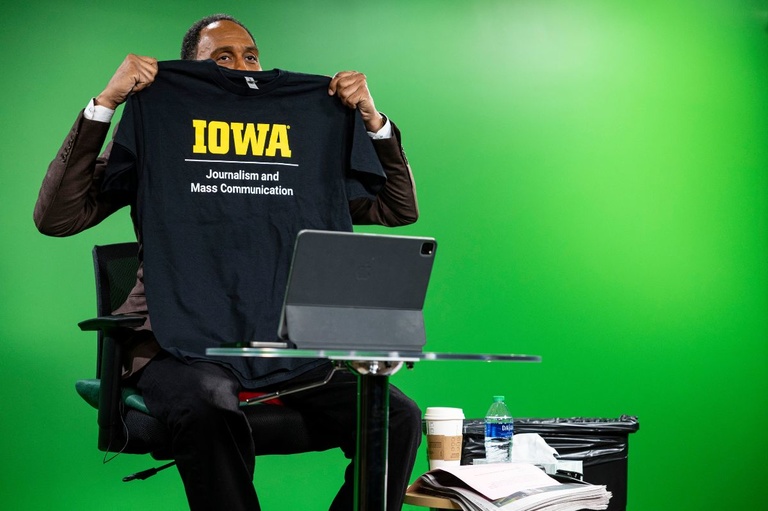 Stephan A Smith holds up a School of Journalism and Mass Communication shirt
