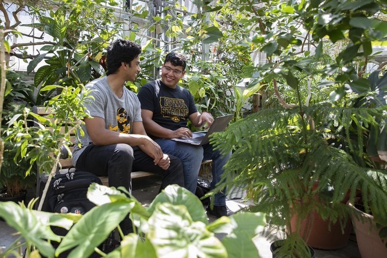 Two students smiling in the greenhouse in Biology Building East