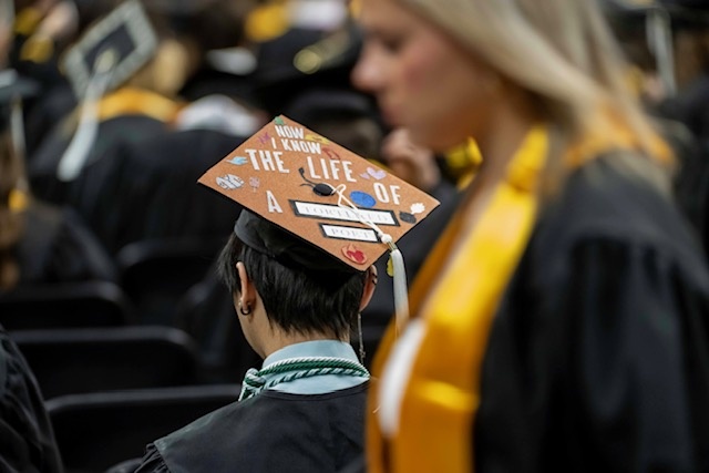 A student in a customized cap reading, "I now know the life..."