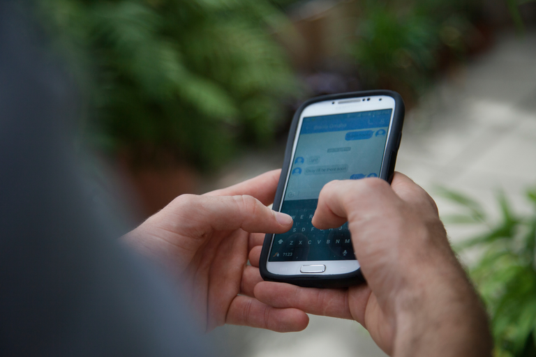close image of hand holding phone, texting