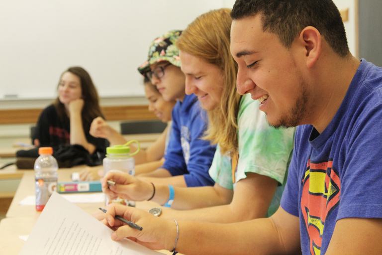 Student holds piece of paper and smiles