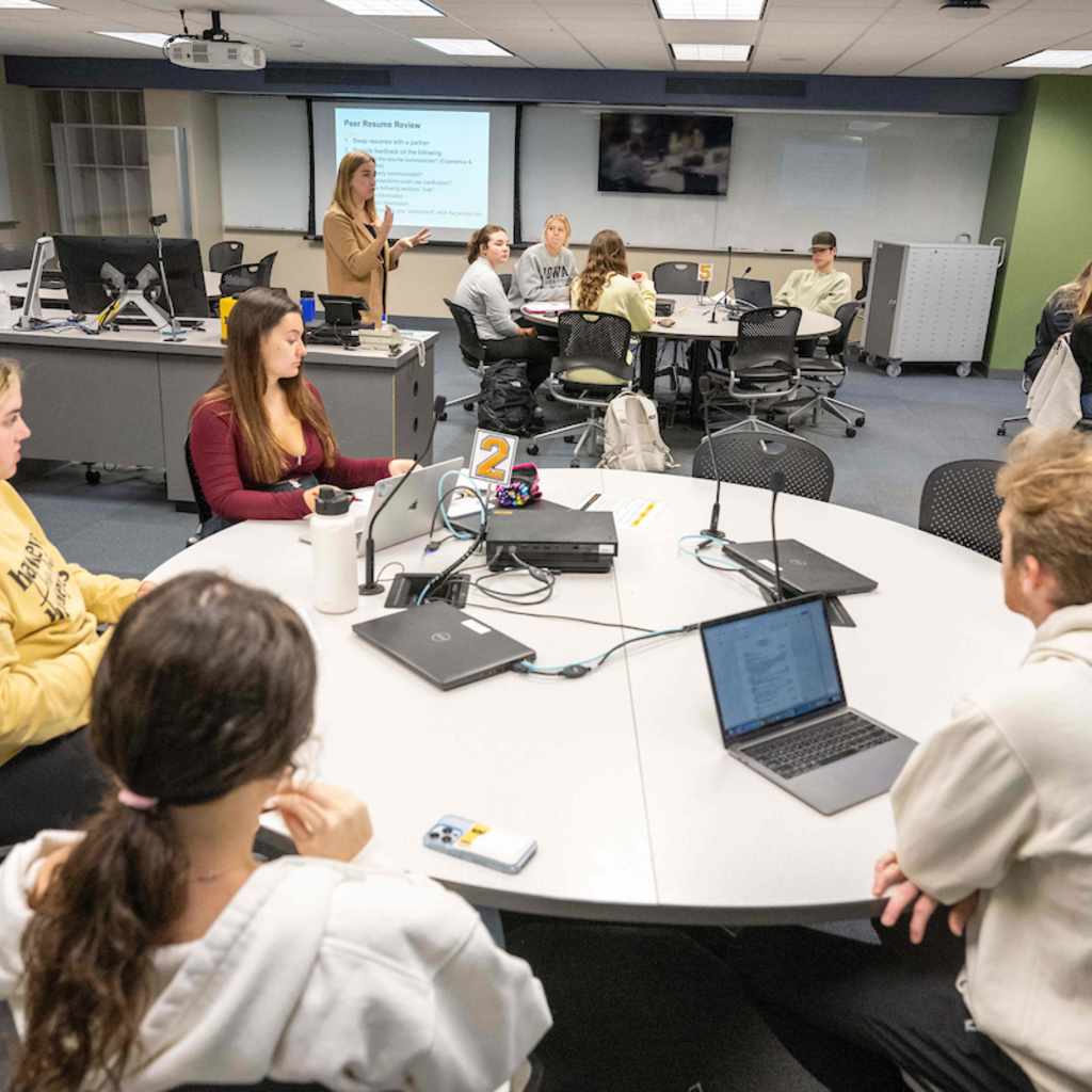 students sitting at round tables with laptops in career center at the University of Iowa