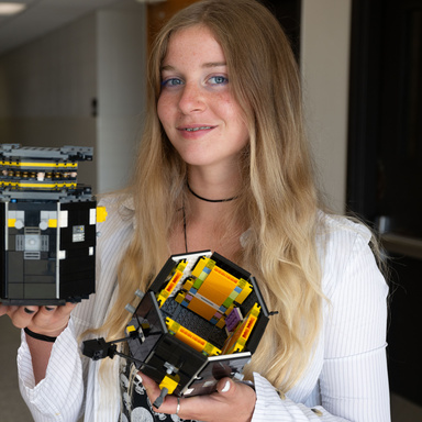 Ava Reed holds the LEGO model of TRACERS satellite