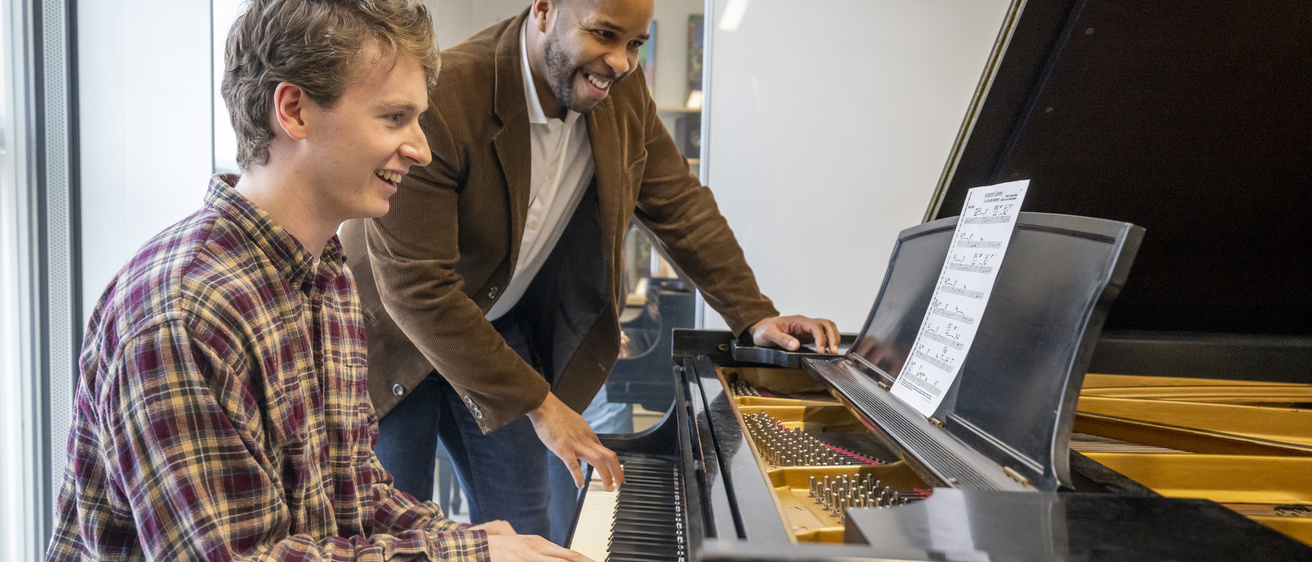 faculty working with student at a piano with a special music project