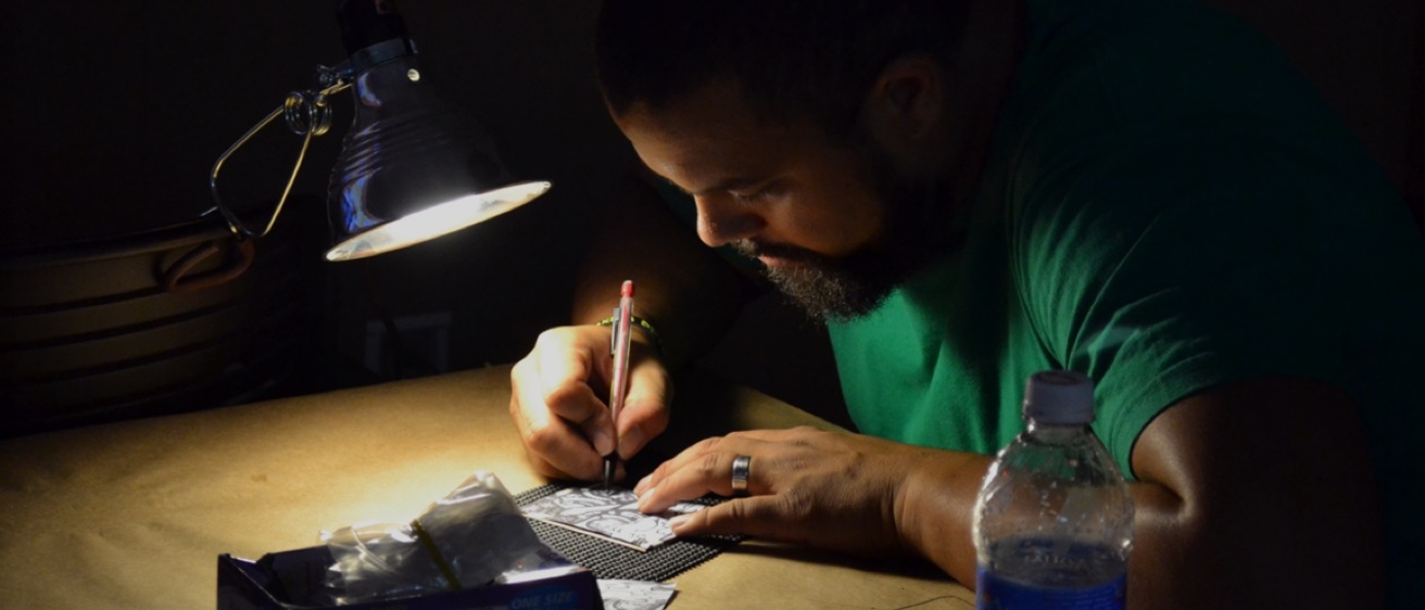 Jeremy Menard working in a dark room with a spotlight on his art