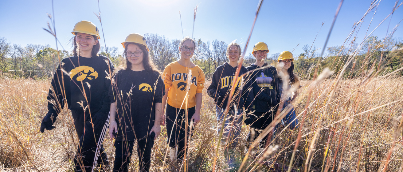 Iowa students walking through prairie grass backlit by sun