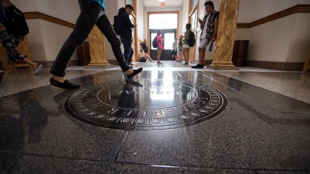 Students walking past the seal on the floor in the 100 level of Schaeffer Hall