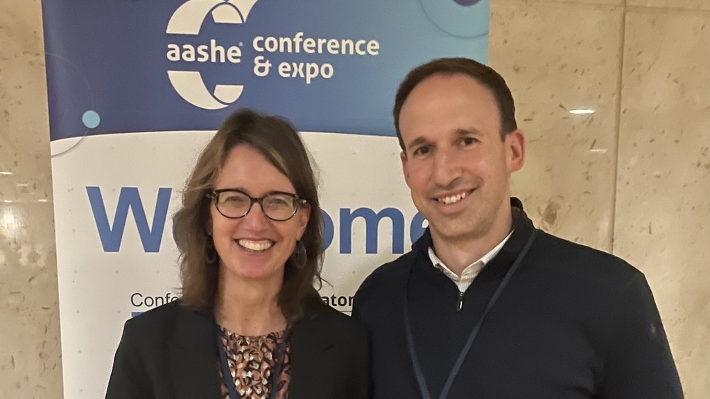 Cornelia Lang and Stratis Giannakouros stand in front of a banner that says "aashe conference and expo"