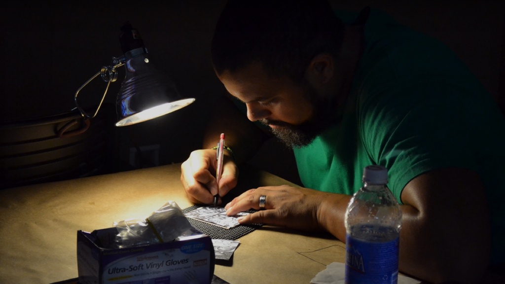 Jeremy Menard working in a dark room with a spotlight on his art