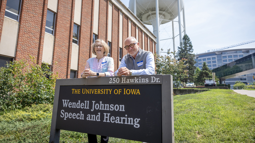 Two people stand next to the Wendell Johnson building sign