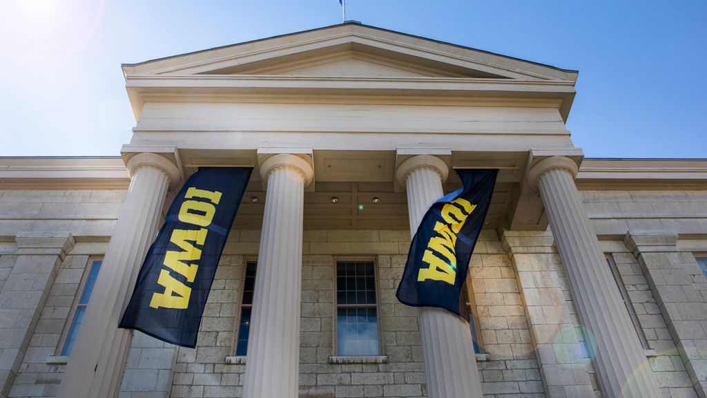 Shaeffer Hall with two black and gold Iowa banners flanking four pillars.