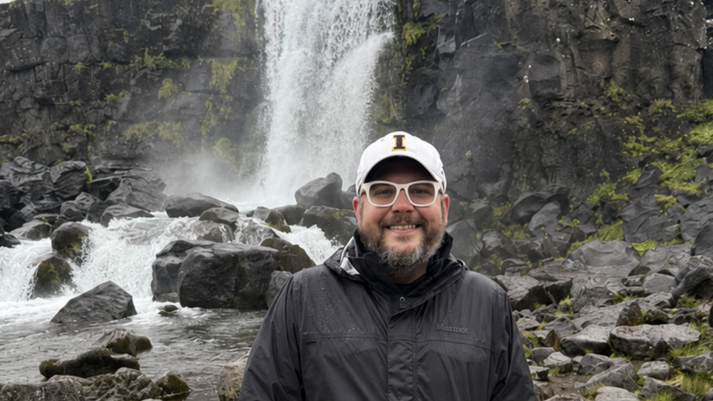 Adam Skibbe standing in front of waterfall in Iceland, 2026.
