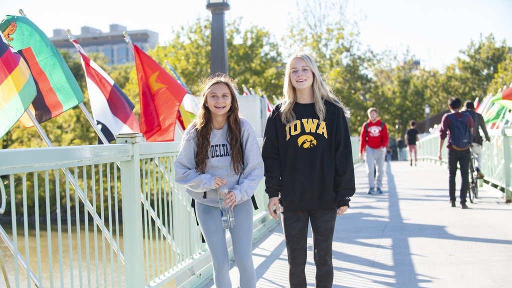 students walking across bridge with international flags