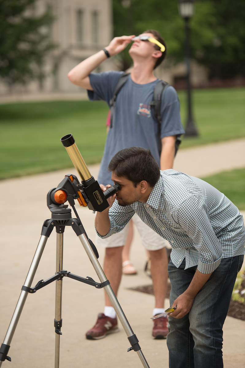 People look at the solar eclipse with telescopes