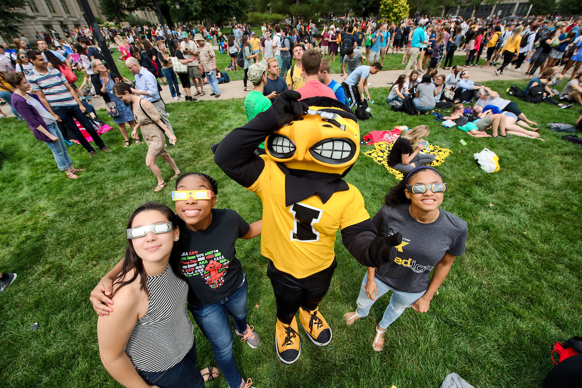 Herky looks at the solar eclipse with three people