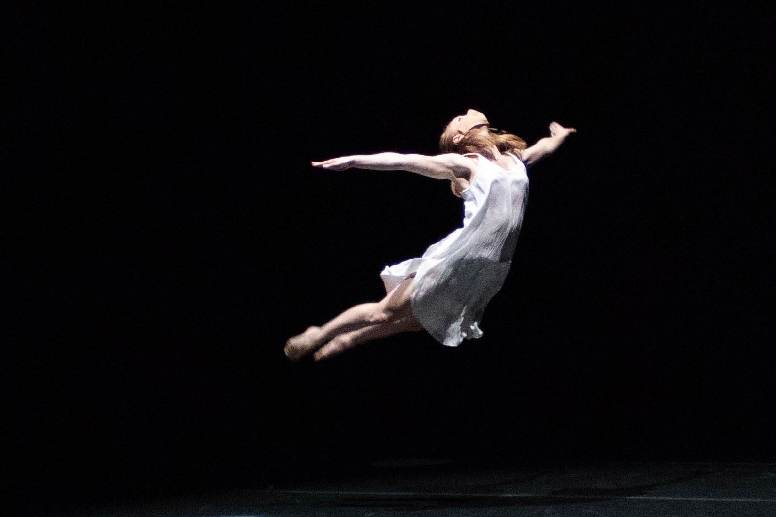 A solo University of Iowa dancer leaping on stage