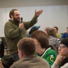An instructor gestures as he speaks into a microphone to the class.