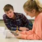 Two students look at a fossil and write.