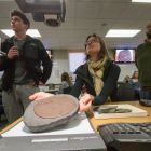 A professor holds a fossil underneath the overhead projector.